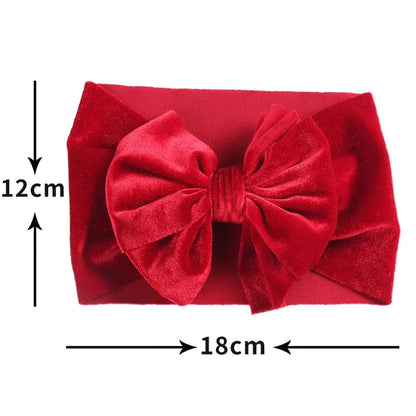 Close-up of a baby's head with a chic red velvet bow winter headband