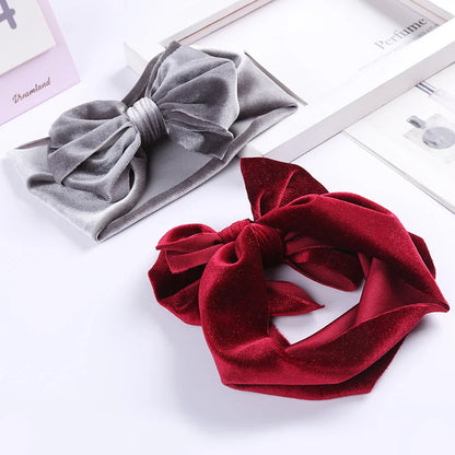 Velvet bow baby headband in a cheerful coral, ideal winter accessory for active girls