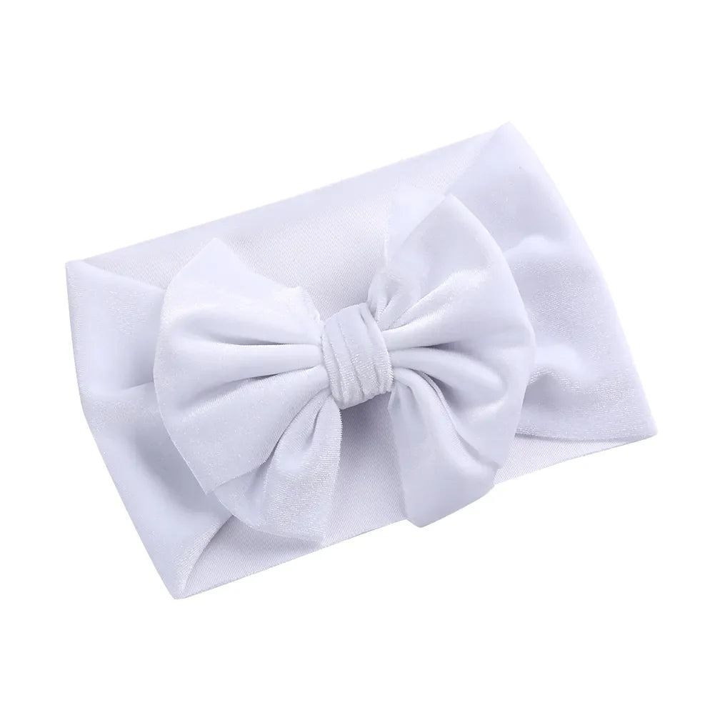 Baby girl with a shimmering gold velvet bow winter headband, festive and soft