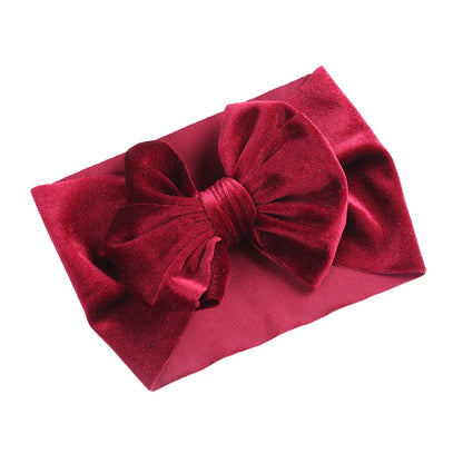 Baby girl modeling a vibrant yellow velvet bow winter headband, elastic and soft