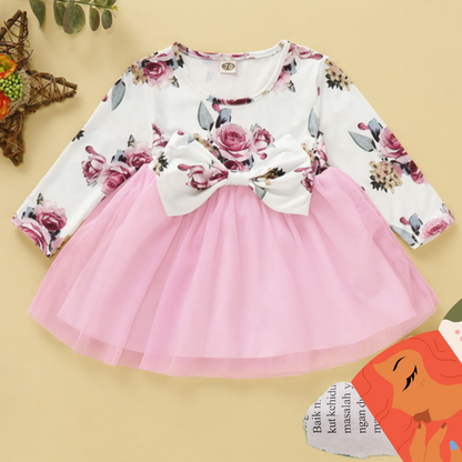 Close-up of a baby girl's long sleeve dress featuring an intricate rose print and bow detail.