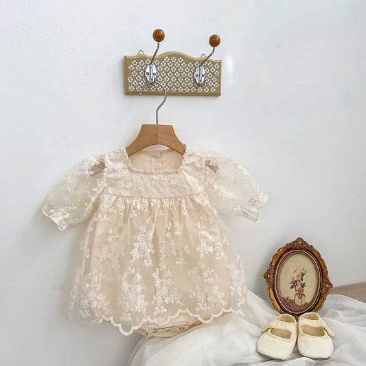 Baby girl's white cotton bodysuit with delicate lace and floral embroidery, perfect for summer.