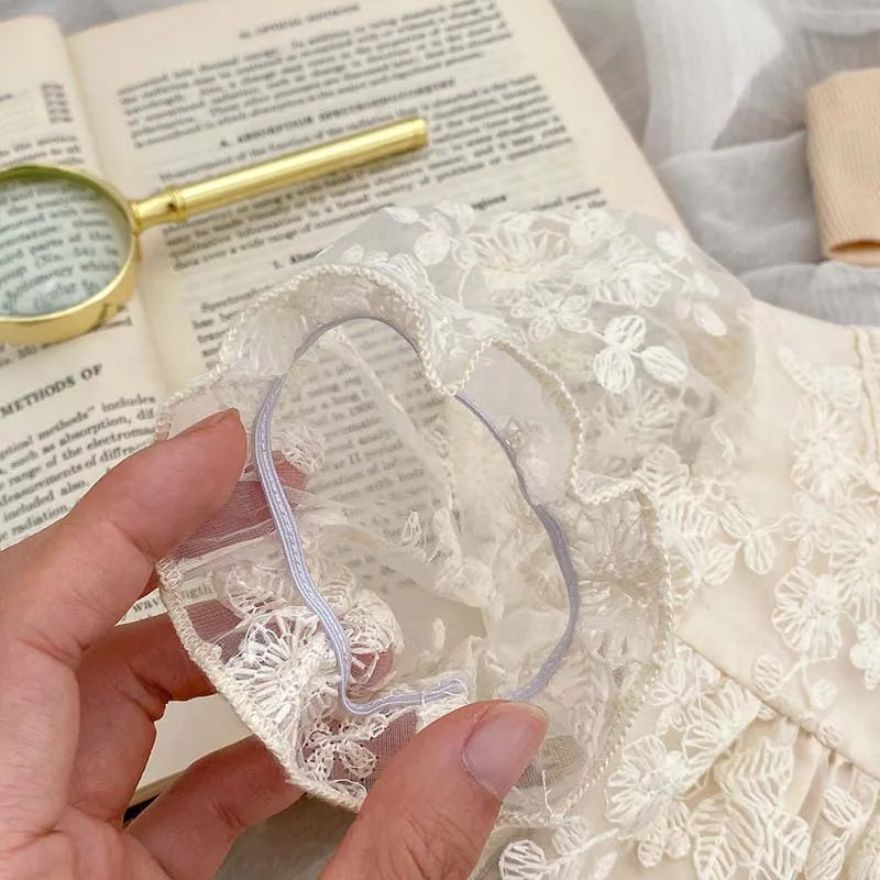 White cotton baby girl's bodysuit, featuring intricate lace and flower embroidery for summer.