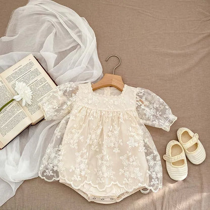 Newborn baby girl in soft cotton lace embroidered summer bodysuit with short sleeves.