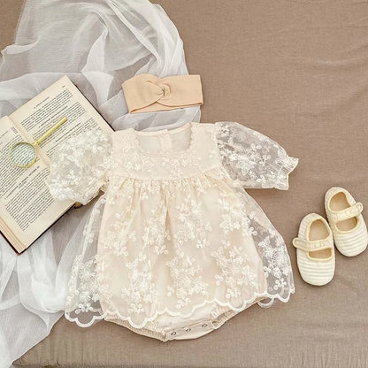 Infant girl's white cotton bodysuit, intricately designed with floral lace and embroidery.