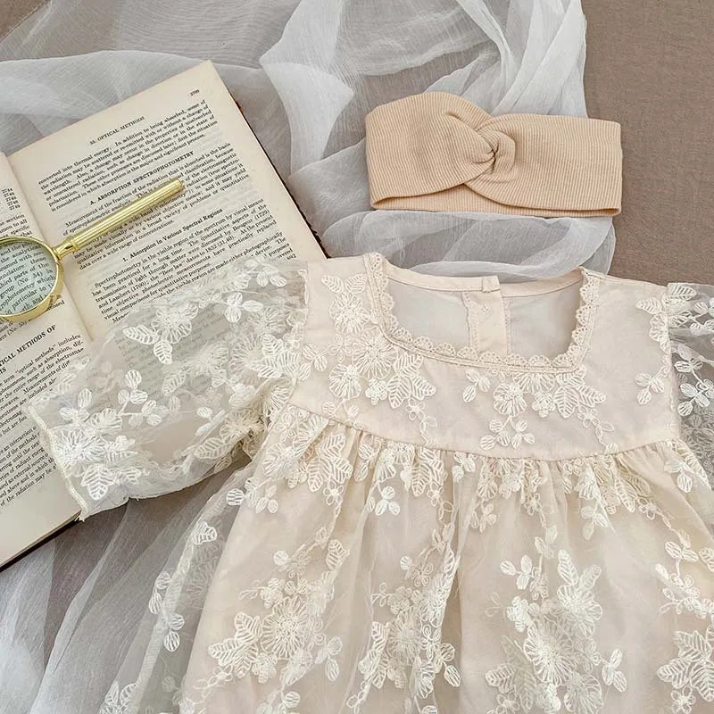Baby girl wearing a comfortable white cotton bodysuit with elegant lace summer detailing.