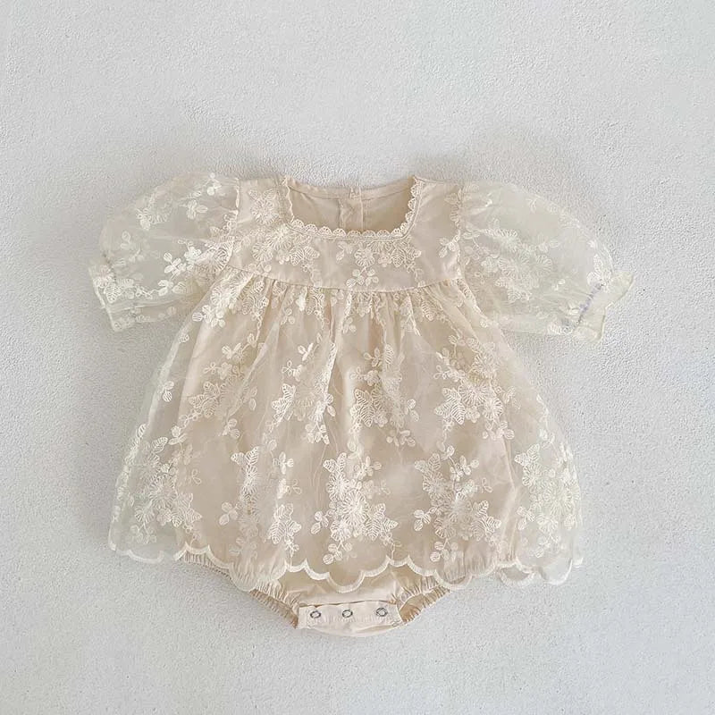 Full shot of a baby girl's summer bodysuit in soft cotton with lace and flower embroidery.