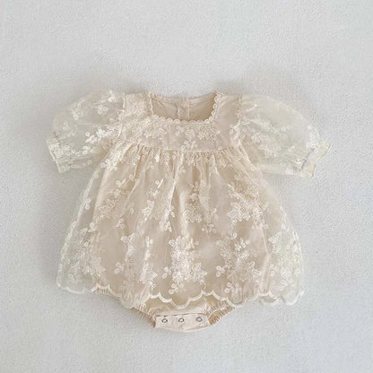 Full shot of a baby girl's summer bodysuit in soft cotton with lace and flower embroidery.