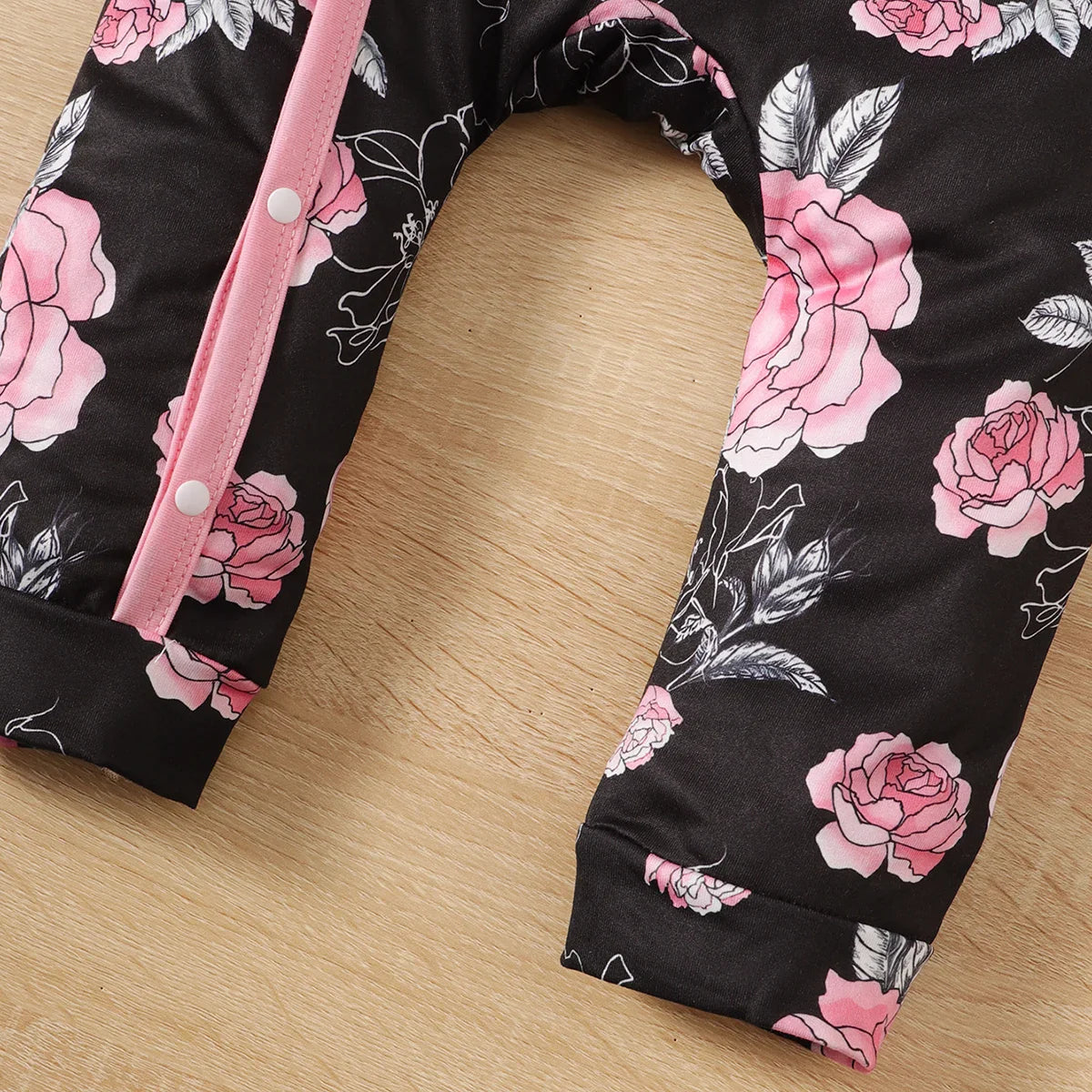 Newborn baby girl wearing a soft, white floral pattern romper with an adorable attached pink bowknot.