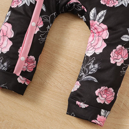 Newborn baby girl wearing a soft, white floral pattern romper with an adorable attached pink bowknot.