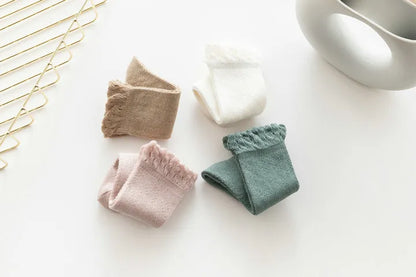 Close-up of elastic cuff on baby girl's hollow knit knee-high socks, secure fit.