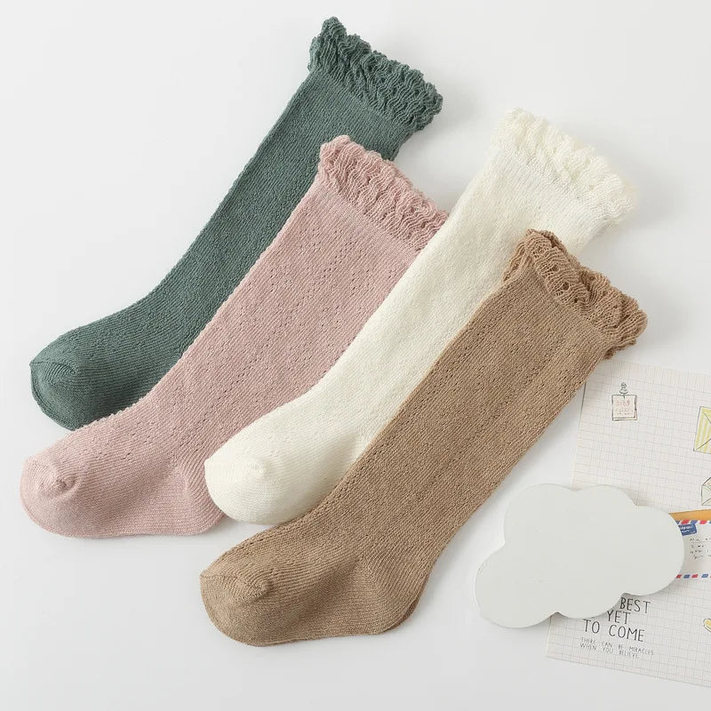 Pair of pink hollow knit knee-high socks for baby girls, soft and comfortable infant apparel.