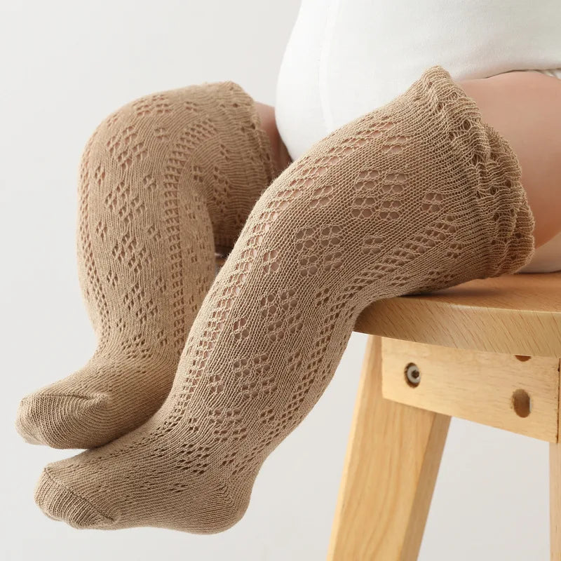Close-up of hollow knit detail on white baby girl's knee-high socks, breathable cotton blend.