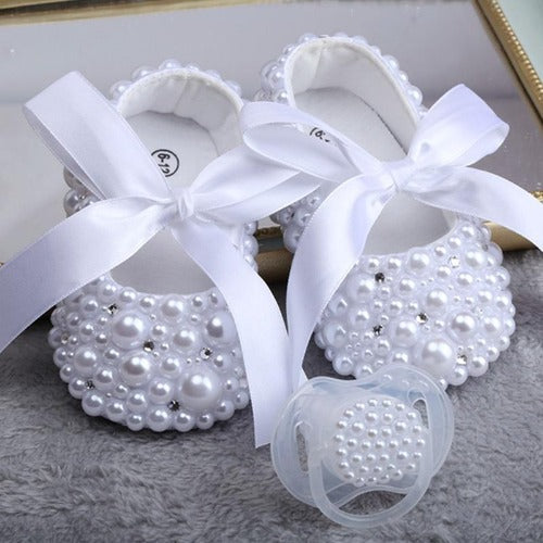 Baby girl's white pearl ribbon first walker shoes and matching pacifier set, ideal for baptism.