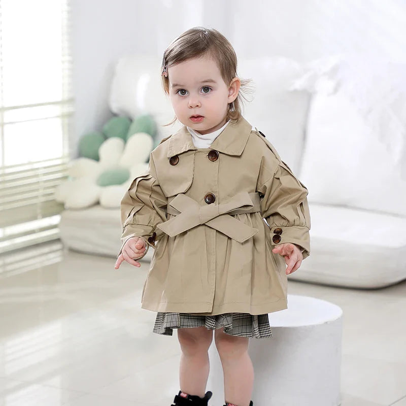 Baby girl modeling a fashionable broadcloth cotton trench coat, perfect for cool autumn days.