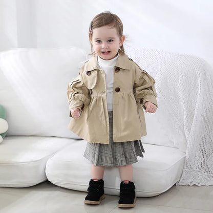 Kids fashion: baby girl wearing a practical cotton trench coat, ideal for spring outerwear.