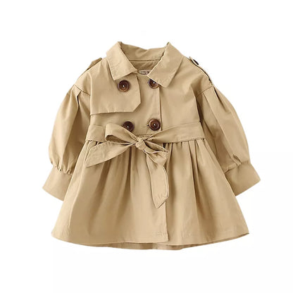 Full shot of a baby girl in a stylish cotton trench coat, ready for autumn weather.