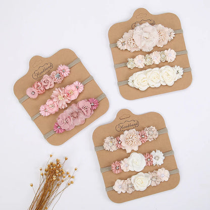 Baby girl wearing a pink artificial flower headband with rhinestones, soft nylon band, ideal for newborns.