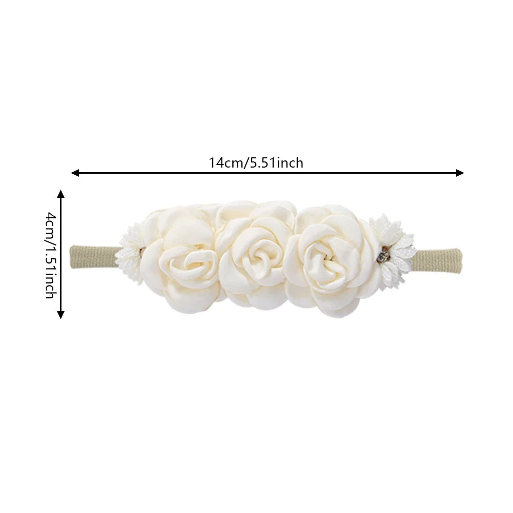 Close-up of a white artificial flower baby headband with sparkling rhinestones on a soft nylon band.