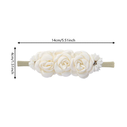 Close-up of a white artificial flower baby headband with sparkling rhinestones on a soft nylon band.