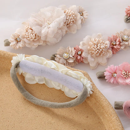 Toddler girl smiling, wearing a beautiful pink floral headband with rhinestone accents, comfortable nylon band.