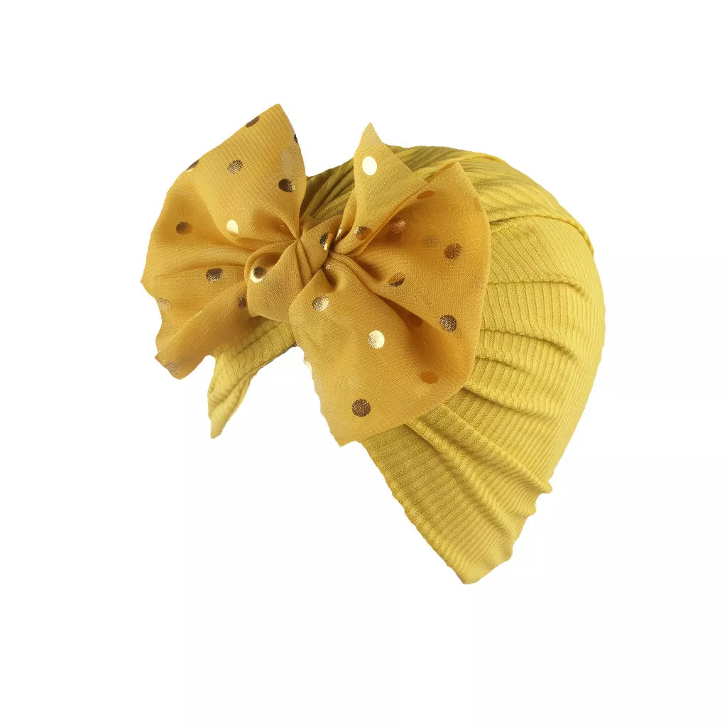 Newborn baby wearing a soft, shiny gold bowknot turban hat.