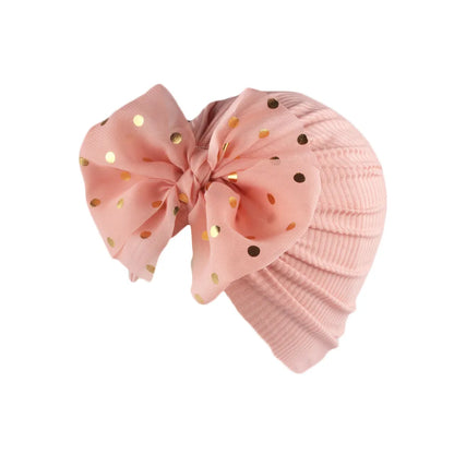 Close-up of a baby girl's head modeling a shiny black bowknot turban hat.
