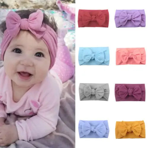 Baby girl wearing pink bowknot headband, soft elastic comfort, infant fashion accessory.
