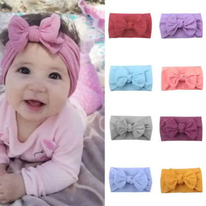 Baby girl wearing pink bowknot headband, soft elastic comfort, infant fashion accessory.