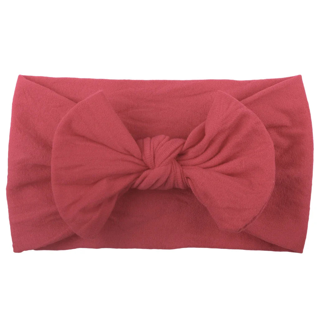 Side view of a baby girl wearing a blue bowknot headband, soft and stretchy.