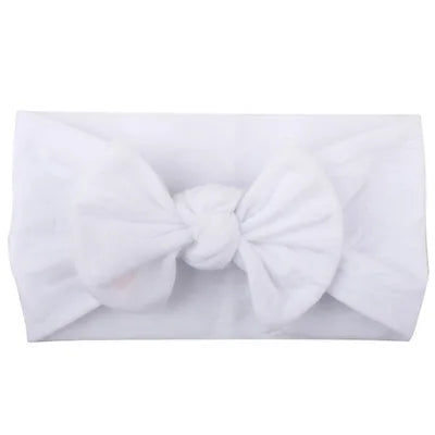 Close-up of a baby's head with a soft elastic white bowknot headband, comfortable wear.