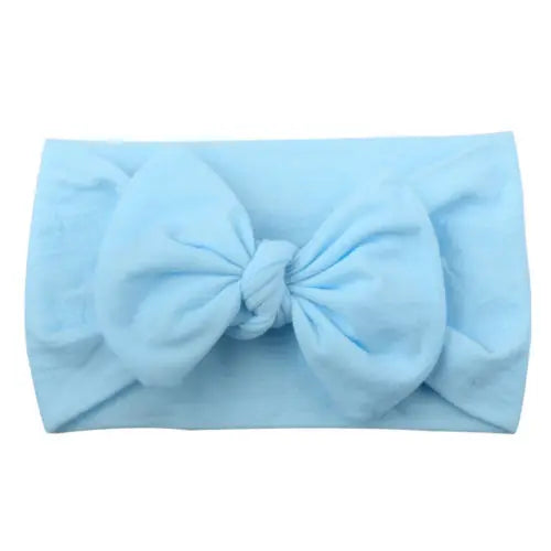 Closeup of a baby girls' soft elastic bowknot headband in white, perfect for newborns.