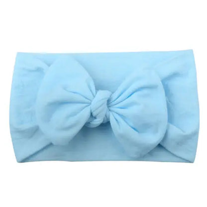 Closeup of a baby girls' soft elastic bowknot headband in white, perfect for newborns.