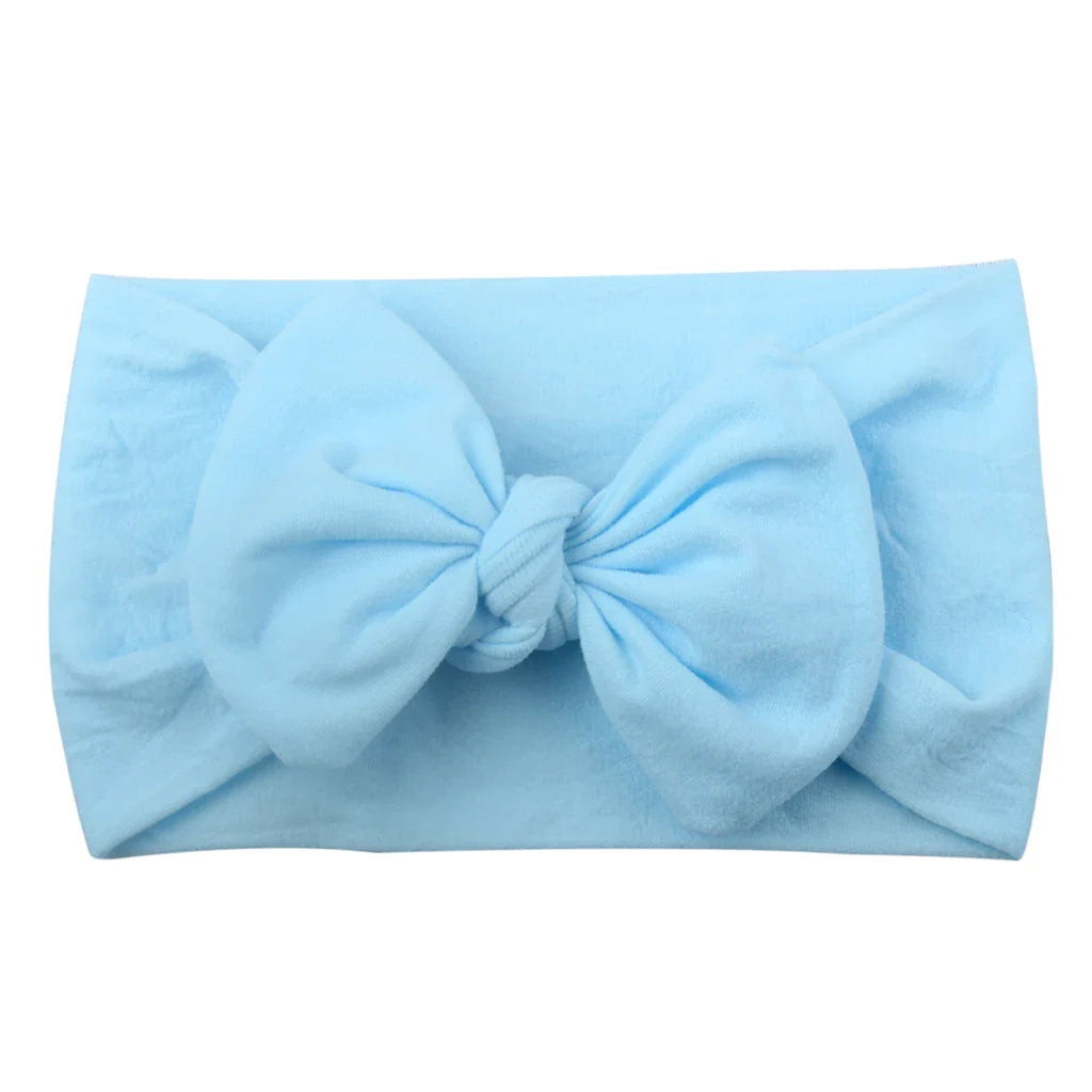 Newborn baby wearing a gentle, soft pink bowknot headband, ideal photo prop.