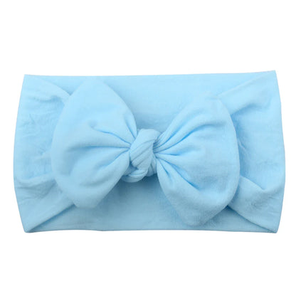 Newborn baby wearing a gentle, soft pink bowknot headband, ideal photo prop.