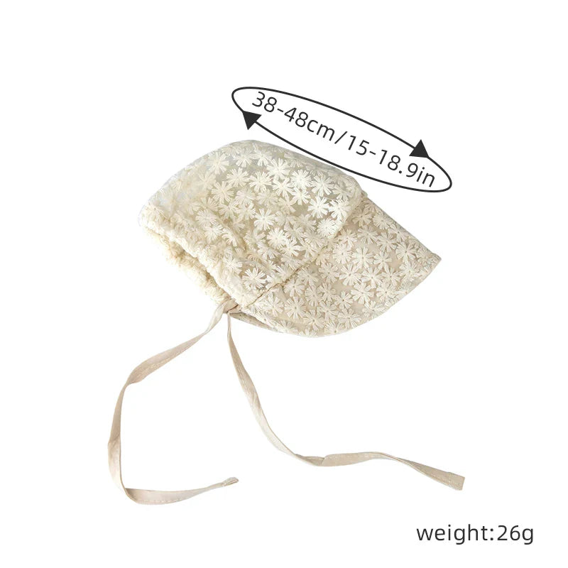 Close-up of a baby girls lace flower sun hat, highlighting the intricate floral design and beige color