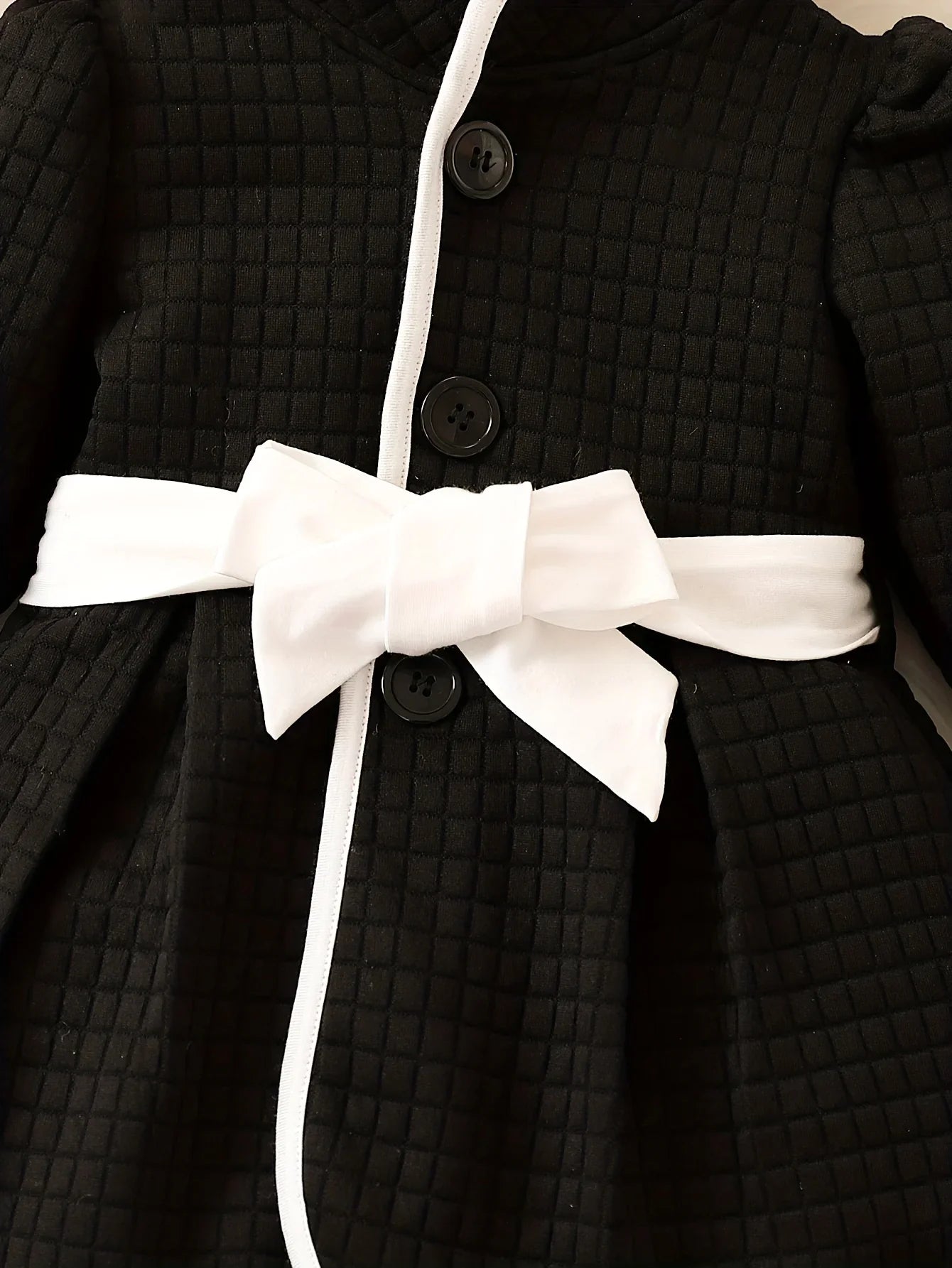 Close-up of puff sleeve on baby girls' thermal dress top, black and white, cozy winter outfit detail