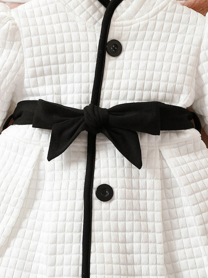 Detail of belted waist on baby girls' thermal dress, black and white print, stylish infant outfit