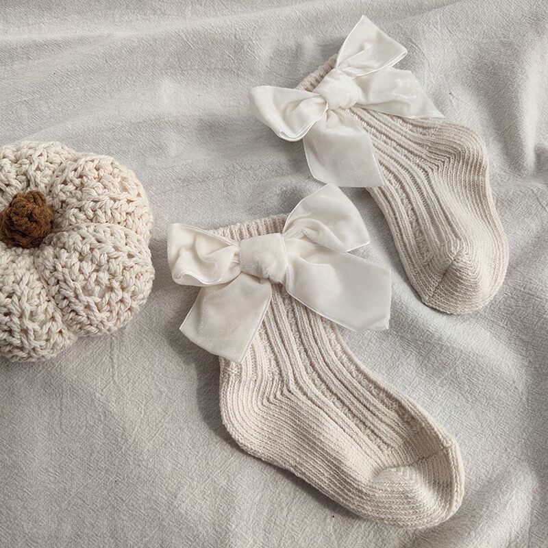 Baby girl wearing warm ankle socks with big bows, soft comfortable fit, perfect for indoor play, stylish baby fashion.