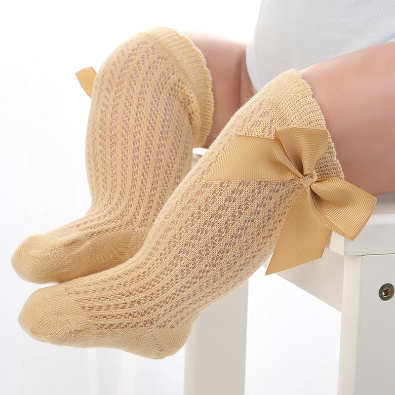 Close-up: soft cotton texture of baby girls' knee-high socks with a bow
