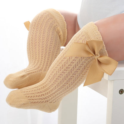 Close-up: soft cotton texture of baby girls' knee-high socks with a bow