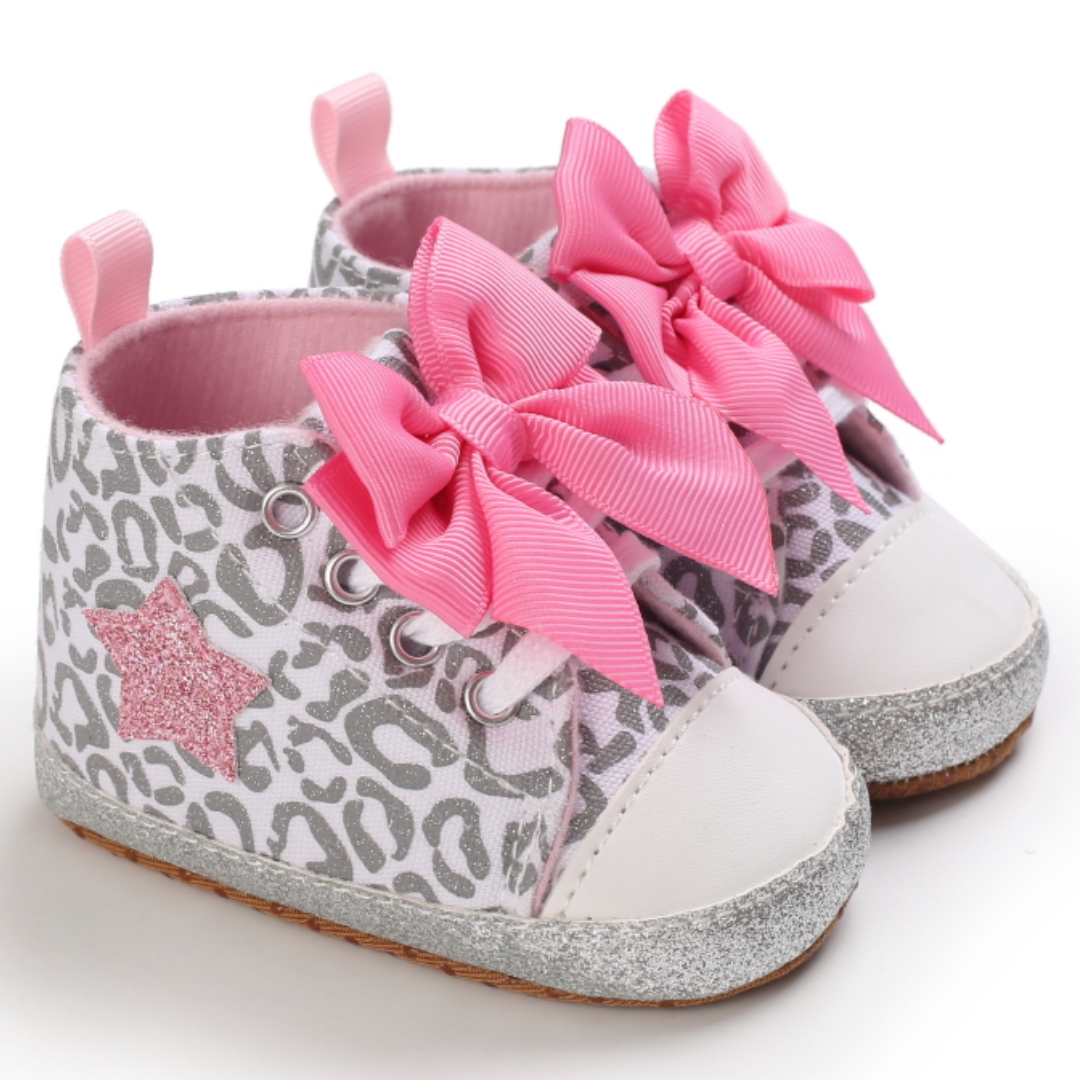 Close-up of a baby girl's hi-top first walker shoe featuring a cute pink bow