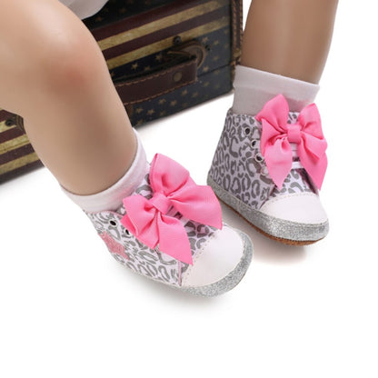 Stylized shot of pink hi-top canvas baby shoes with bows, for active toddlers