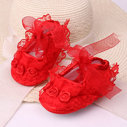 Close-up of elegant baby girls' satin soft sole shoes with intricate floral lace detail.