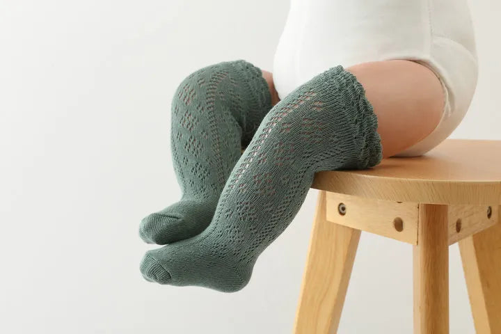 Detailed view of the elastic cuff on hollow knit knee-high socks for baby girls, secure fit