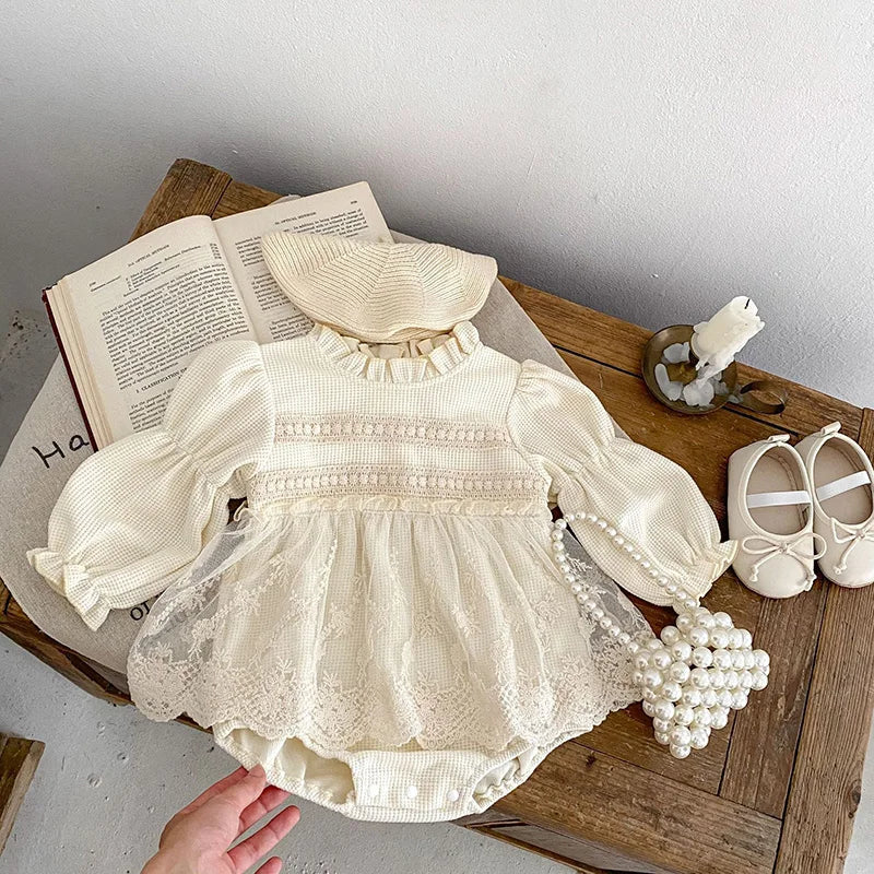 Close-up of the waffle knit texture on a pink baby girl's bodysuit with puff sleeves, lace accent.