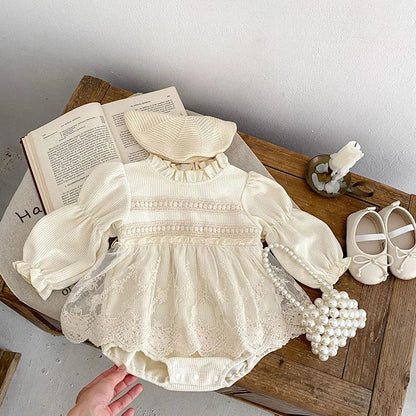 Close-up of the waffle knit texture on a pink baby girl's bodysuit with puff sleeves, lace accent.