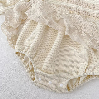 High-quality cotton baby girl's pink waffle knit bodysuit featuring puff sleeves and lace details.