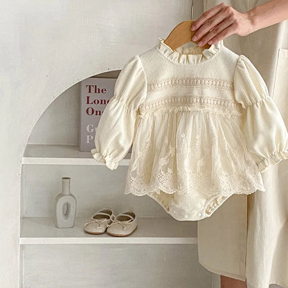 Lay flat of a pink waffle knit baby bodysuit for girls, highlighting puff sleeves and lace trim.