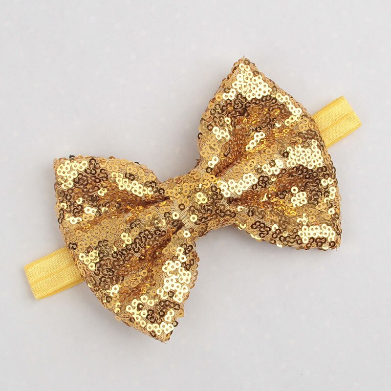 Baby model wearing a sequin bow headband, showing its comfortable fit and charming style